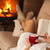 Woman enjoying a book and a hot chocolate drink by lying the fir stock photo © ilona75