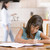 Young girl in kitchen doing homework with woman in background stock photo © monkey_business