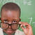 Schoolboy looking over his glasses in front of a blackboard stock photo © wavebreak_media