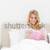 A woman reading a book and smiling as she sits in bed. The alarm clock on the desk beside her. stock photo © wavebreak_media