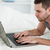 Young man using a laptop while lying on his belly in his bedroom stock photo © wavebreak_media