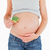 Pregnant woman holding a broccoli while standing against a white background stock photo © wavebreak_media