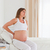 Charming pregnant female having a back pain while sitting on a bed in her apartment stock photo © wavebreak_media