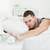 Exhausted man switching off his alarm clock in his bedroom stock photo © wavebreak_media