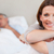 Smiling woman on the bed with reading husband in the background stock photo © wavebreak_media