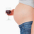 View profile of a young pregnant woman holding a glass of red wine while standing against a white ba stock photo © wavebreak_media