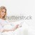 A woman is sitting up in bed, with a quilt over her waist, her arms just in front of her as she smil stock photo © wavebreak_media